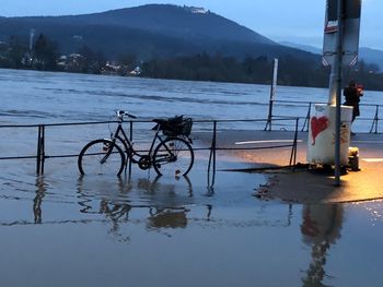 Bicycle by lake against sky during winter