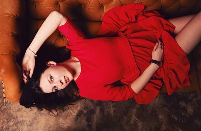 High angle portrait of beautiful woman lying on sofa at home