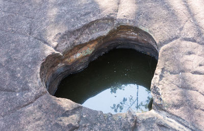 Low angle view of stone wall with reflection in water