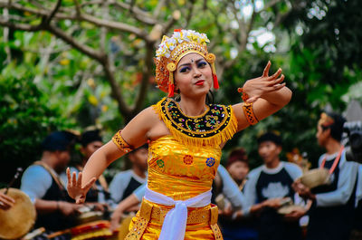 Portrait of young woman dancing against blurred background