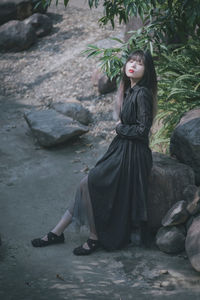 Portrait of young woman sitting on rock