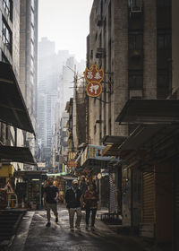 People walking on road amidst buildings in city