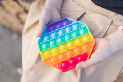 Midsection of person holding multi colored toy