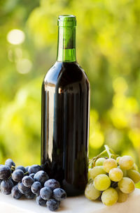 Close-up of wine bottle amidst grapes on table