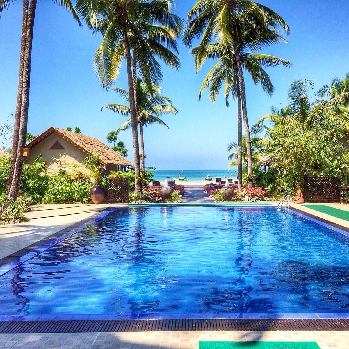 water, sea, tree, palm tree, blue, horizon over water, swimming pool, building exterior, built structure, architecture, beach, tourist resort, sky, sunlight, turquoise colored, nature, shore, scenics, house, growth