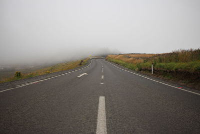 Road leading towards fog against sky