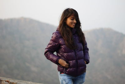 Young woman standing against mountains