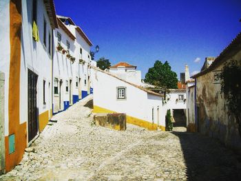 Alley amidst buildings in town against clear blue sky