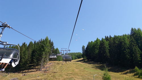 Ski lift amidst trees against clear sky