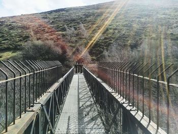 Footbridge over trees against sky