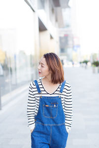 Young woman looking away while standing in city