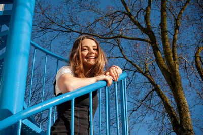 Portrait of smiling woman against blue sky