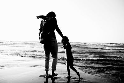 Mother and child at beach against clear sky