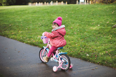 Full length of girl riding bicycle on road