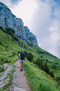 Rear view of man walking on mountain against sky