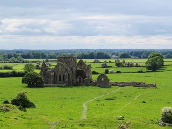 Old ruins in field against cloudy sky