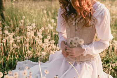 Midsection of woman with umbrella on field