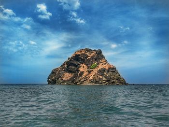 Rock formation in sea against blue sky