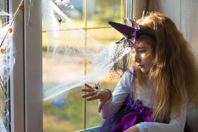 Cute girl sitting by window at home