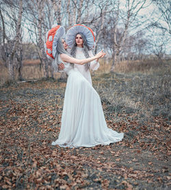 Woman standing by tree in forest