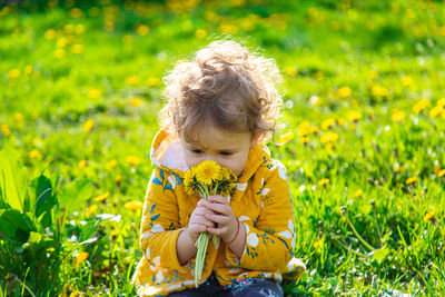 Side view of girl picking flowers on field