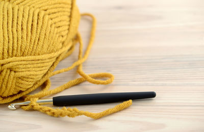 Close-up of yellow wool with needle on table