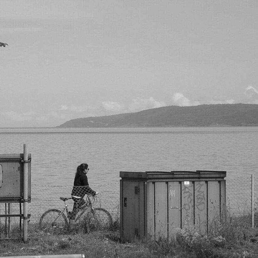 rear view, water, mountain, lifestyles, full length, leisure activity, sky, standing, lake, tranquility, sea, nature, men, looking at view, railing, tranquil scene, scenics, sitting