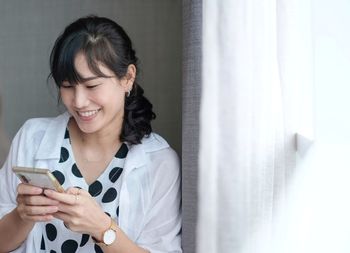 Portrait of smiling young woman using mobile phone