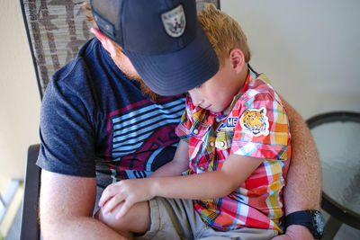 High angle view of son sitting on father at home