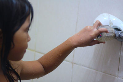Girl turning shower knob while taking bath in bathroom