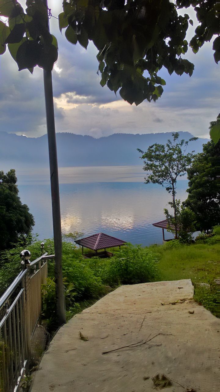 tree, sky, mountain, tranquility, built structure, tranquil scene, mountain range, scenics, cloud - sky, cloud, nature, landscape, architecture, building exterior, beauty in nature, growth, green color, house, day, hill