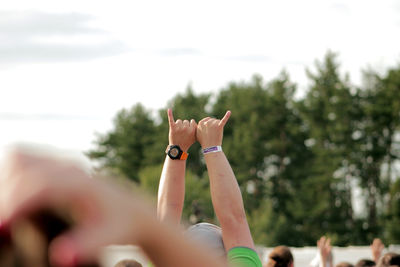 Cropped image of man with arms raised against sky