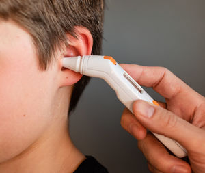 Close up of child getting temperature taken with an ear thermometer.