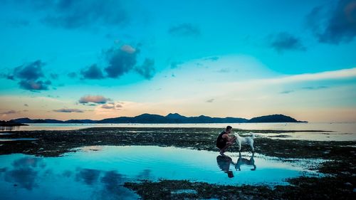 Man standing on beach against blue sky