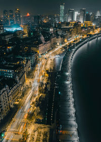 High angle view of illuminated street amidst buildings in city at night