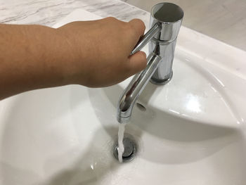 Midsection of person holding faucet in bathroom