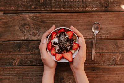 Directly above shot of person holding ice cream on table