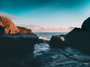 Rock formation by sea against sky