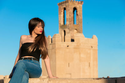 Young woman sitting against historical building