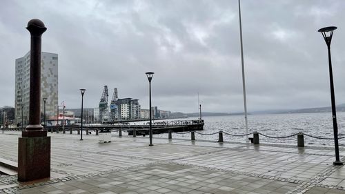 Pier on sea by city against sky