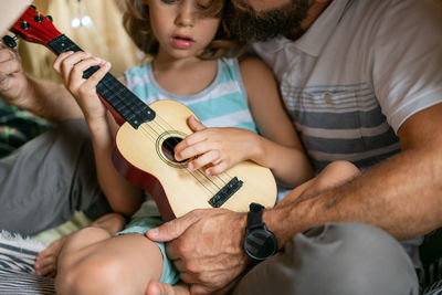 Portrait of a 6 year old boy and his father having fun playing guitar in teepee tent.