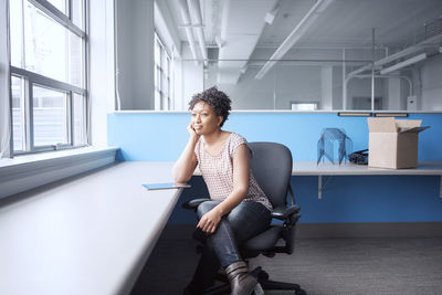 Thoughtful businesswoman looking away while sitting on chair in office