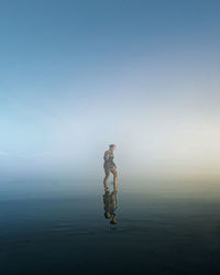 Rear view of woman standing on beach against clear sky