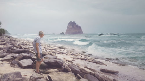 Man looking at sea shore against sky