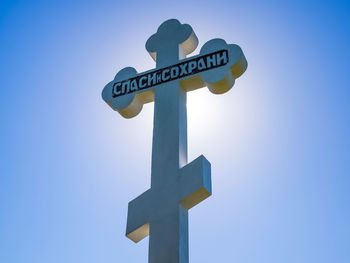 Low angle view of road sign against clear blue sky