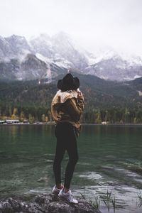 Full length rear view of man standing on mountain lake