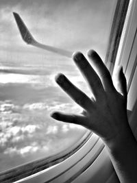 Midsection of person against sky seen through airplane window