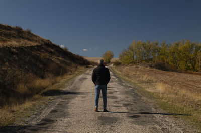 Portrait of adult man in winter cloth on a country road against blue sky. shot in castilla y leon.