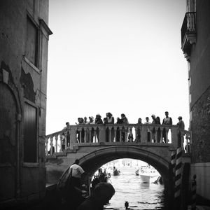 People on arch bridge against clear sky