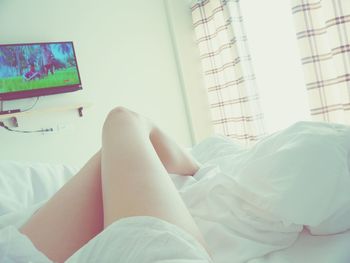 Low section of woman relaxing on bed at home